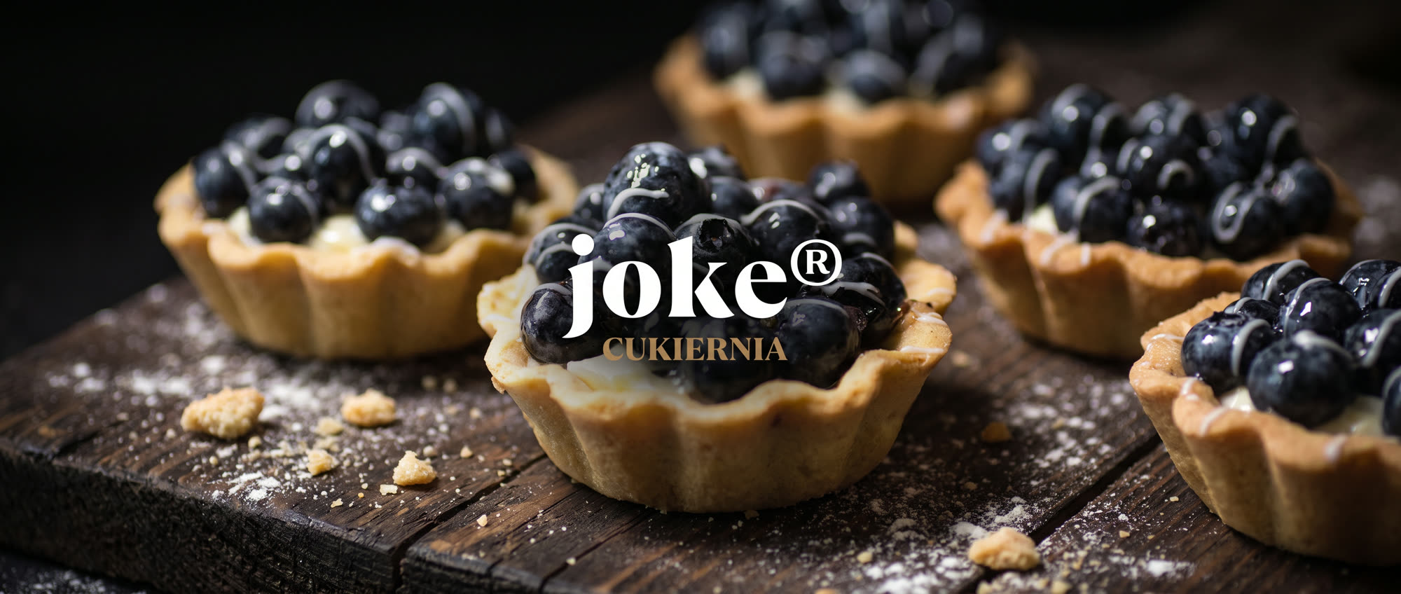 joke® Cukiernia - logo na tle babeczek z jagodami